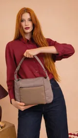 Bandolera de diseño práctico con combinación de texturas en tonos tierra, confeccionada en tela y símil cuero. Cuenta con un compartimento principal con cierre, un bolsillo frontal con cierre y correa ajustable para llevar al hombro o cruzada.