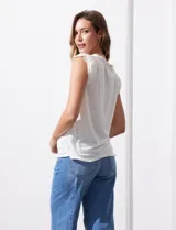 Remera blanca de modal, marca French Laundry, con escote en V. Presenta apliques de puntilla en las mangas y el escote, y un detalle fruncido en los hombros.