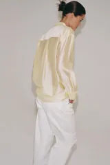 Camisa de mujer fluida de ZARA WOMAN COLLECTION, confeccionada en hilatura con mezcla de lyocell. Presenta escote en pico, manga larga con puños marcados y bajo asimétrico, con cierre frontal de botones ocultos.