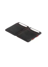 Billetera artesanal de cuero marrón oscuro con costuras en hilo rojo. Presenta un sistema de sujeción elástico en el lateral con detalles de colores (rojo, amarillo, azul) y ranuras para tarjetas en el exterior.