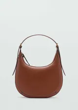 Bolso de hombro tipo hobo en color marrón, con diseño de media luna, costuras decorativas visibles y asa ajustable con hebillas laterales.