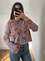 Sweater de tejido de punto con diseño estampado tipo paisley en tonos marrones y azules, de corte recto y manga larga.