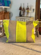 Sobre de gamuza de diseño bicolor en tonos verde lima y marrón, con costuras visibles y tiras laterales con borlas colgantes.