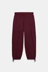 Pantalón de punto color bordó, tiro medio, con cintura elástica y puños ajustables con lazada en los tobillos.