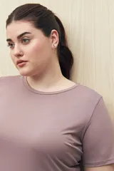 Remera deportiva color lila de manga corta con calce relajado y corte horizontal en la parte inferior.