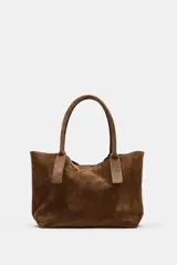 Bolso tipo shopper de piel en color marrón, con doble asa de hombro, bolsillo interior con cremallera y doble sistema de cierre con botón imantado y tira con botón metálico.