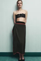 Pareo tipo pañuelo de viscosa con diseño cruzado y cierre mediante lazada en la cintura. Presenta un estampado de lunares pequeños sobre fondo bordó y un panel lateral en color verde oscuro con microestampado, ambos con bordes definidos.