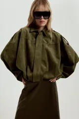 Chaqueta de efecto ante color marrón claro, con cuello solapa, manga larga con trabillas en los hombros y bajo abullonado. Cierre frontal con cremallera y botones ocultos por solapa.