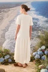 Vestido midi color crudo de manga corta, con corte en la cintura y falda holgada con volados y detalle de pequeño bordado de hongo en el pecho.