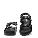 Sandalias de plataforma plana Miss Carol modelo Naira, color negro con doble tira ajustable con hebillas metálicas plateadas y suela dentada.