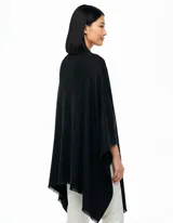 Ruana de tejido soft color negro, con cuello en V y un nudo o pasador frontal que ajusta la prenda. Los bordes tienen terminación desflecada.