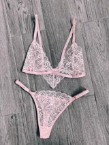 Conjunto de lencería compuesto por un bralette de encaje con breteles regulables y una bombacha tipo tanga a juego, ambos en color rosado.