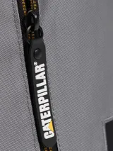 Bolso tipo bandolera Caterpillar color gris, con correa ajustable negra, compartimento principal con cierre, bolsillo frontal vertical con cremallera y detalles de la marca en amarillo y negro.