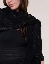 Pashmina rectangular negra confeccionada en tejido liviano y vaporoso con sutil transparencia y caída fluida, adornada con pequeños apliques de strass.