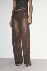 Pantalón de tiro alto, pierna recta y forro interior tipo shorts. Confeccionado en tejido negro con bordado floral en lentejuelas y abalorios dorados.