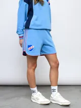 Short de felpa celeste, de corte deportivo, con detalles de pipings tricolor en los bordes y escudo del Club Nacional de Football aplicado en la pierna.