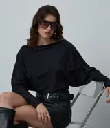 Blusa de microfibra con diseño de manga murciélago, escote amplio y caída holgada. Prenda de manga larga confeccionada en tejido ligero y resistente.