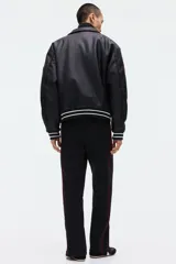 Pantalón jogger negro de corte relajado, con cordón ajustable en la cintura, franjas laterales rojas y estampado con la palabra "Honda" en la pierna izquierda.