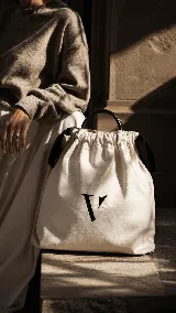 Bolso matero de cuero marrón con diseño estructurado, costuras decorativas en el borde superior y bolsillo frontal con cierre de botón tipo colmillo. Incluye asas de mano y espacio interior diseñado para transportar termo y accesorios de mate.