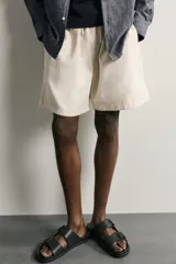 Bermuda de algodón en color beige, con corte relaxed fit, cintura elástica con cordón ajustable y bordado a tono en la pernera.