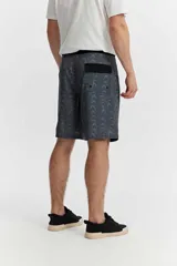Short de baño estilo surf color gris, de largo medio, con estampado geométrico abstracto y cordón ajustable en la cintura. Incluye bolsillo trasero con solapa.