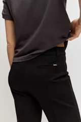 Pantalón negro de corte flare, tiro alto y diseño ajustado en la parte superior con piernas acampanadas.