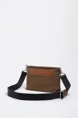 Bolso bandolera de tamaño mediano confeccionado en nylon negro, con estructura blanda, asa regulable de tejido, logo metálico de la marca en el frente y cierre con cremallera.