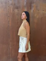 Falda corta tipo wrap de cuero color crudo, con diseño cruzado y ajuste mediante tiritas laterales.
