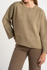Sweater de punto color tostado con calce oversize, cuello redondo y mangas largas anchas. Presenta terminaciones acanaladas en cuello, puños y ruedo.