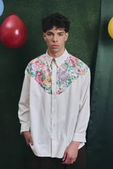 Camisa de corte oversize con mangas largas y puños abotonados. Presenta un diseño bicolor con cuerpo blanco y un canesú delantero con estampado floral multicolor.