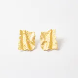 Par de aros tipo caravana con diseño rectangular de superficie irregular y texturizada en acabado dorado.