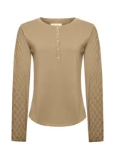 Remera de manga larga color beige, con cuello redondo y cierre frontal parcial con botones. Presenta un diseño de tejido trenzado con textura de rombos en las mangas y cuerpo liso.