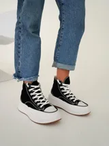 Championes tipo botita de caña alta con diseño bicolor, cuerpo en color negro y suela de plataforma gruesa en color blanco con base de goma.