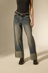 Pantalon jean de corte recto y tiro medio, con un lavado desgastado y un dobladillo ancho en la parte inferior que deja ver el revés de la tela con costuras en contraste.