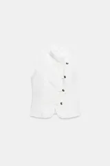 Top de denim blanco sin mangas, con cuello mao y cierre frontal cruzado con trabillas y botones metálicos.