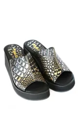 Zueco con plataforma de cuero negro con estampado croco en tonos dorados.