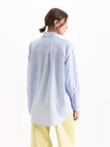 Camisa de poplín de tencel de silueta recta y calce holgado, con diseño a rayas celestes y verdes, cuello camisero con remaches en forma de corazón en las puntas, bolsillo frontal en el pecho y mangas largas con puños anchos.