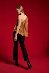 Blusa de poliéster color negro, con diseño asimétrico de un solo hombro, plisado ligero y corte holgado.