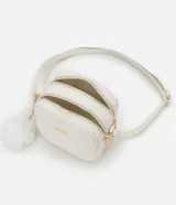 Cartera bandolera Satinato pequeña de color blanco, de diseño estructurado con textura floater, cierre de cremallera y detalles metálicos dorados. Incluye una correa larga ajustable y un pompón decorativo colgante.