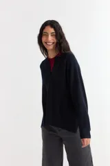 Sweater de tejido de punto color azul marino, con cuello abierto tipo polo y tajos laterales en el ruedo. Presenta mangas largas con puños acanalados y un corte holgado.