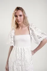 Vestido largo de encaje blanco con cuerpo fruncido elastizado, mangas cortas abullonadas y falda con vuelo.