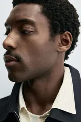 Cazadora cropped fit color azul marino, confeccionada en tejido de algodón. Presenta cuello solapa, manga larga con puño abotonado, bolsillos frontales de vivo y un bolsillo interior. El cierre es frontal con cremallera.