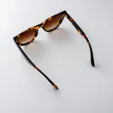 Lentes de sol con armazón de carey en tonos marrones y negros, y cristales degradados. Tienen un diseño moderno y versátil.