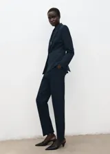 Blazer ajustado color azul marino, con cuello en V, solapas con muesca y cierre frontal de botones. Cuenta con bolsillos delanteros con solapa y bolsillo ribeteado en el pecho, mangas largas con puños abotonados, abertura en la parte trasera del bajo y forro interior.