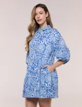 Vestido corto camisero de Elan, con diseño estampado en tonos de azul, cuello camisero clásico, mangas 3/4 abullonadas con elástico en los puños y falda con volantes fruncidos.