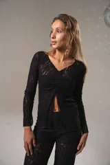 Top negro de encaje con jareta en la parte superior, abertura en el centro y en el final de las mangas largas.