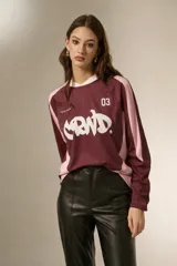 Remera de manga larga estilo deportivo, confeccionada en tejido técnico. Presenta un diseño color block en tonos bordó y rosa, con cuello mao y estampado gráfico frontal en color blanco.