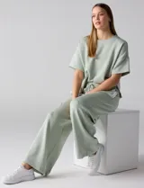 Conjunto de buzo de manga corta con hombros caídos y escote redondo, acompañado de un pantalón tipo wide leg de tiro alto con cintura elástica y cordón de ajuste, en color verde.