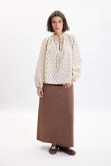 Falda larga de jean color marrón con diseño de paneles y corte evasé.