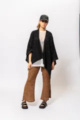 Ruana negra con lurex dorado, de corte cuadrado y mangas 3/4.